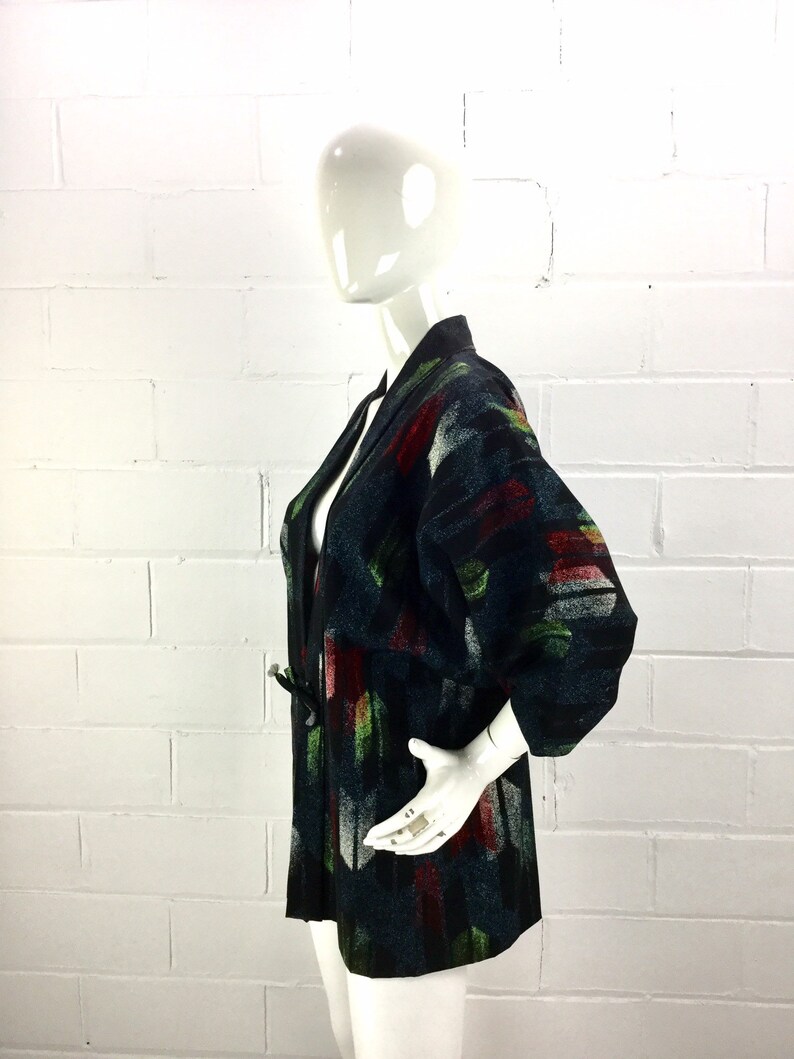 May include: A black and green patterned kimono with a long sleeve and a tie belt. The kimono is made of a soft, textured fabric.