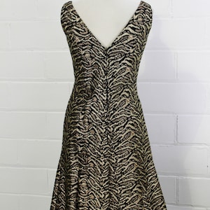 May include: A sleeveless dress with a V-neckline and a black and gold animal print pattern.