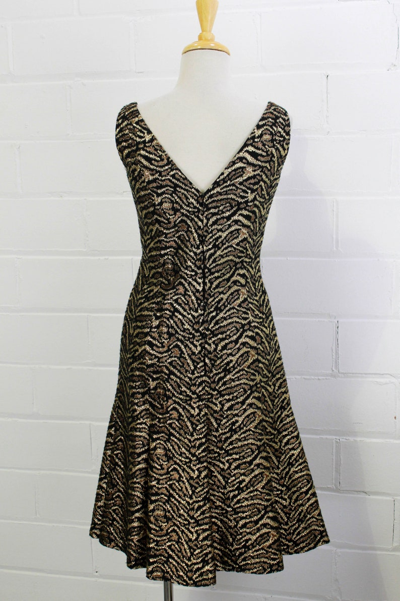 May include: A sleeveless dress with a V-neckline and a black and gold animal print pattern.