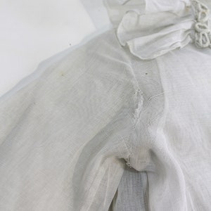 May include: White sheer blouse with a ruffled collar and a small tear in the sleeve.