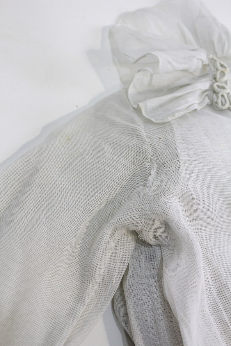 May include: White sheer blouse with a ruffled collar and a small tear in the sleeve.
