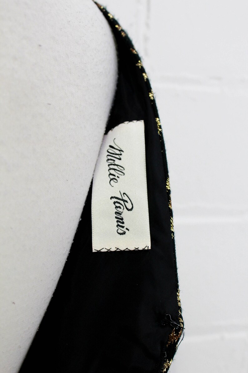 May include: A black and gold dress with a white tag that says "Millie Paris".