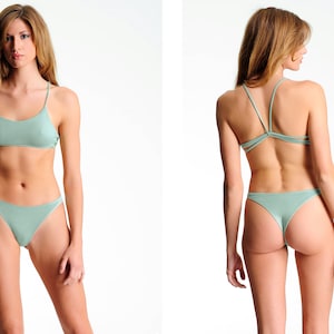 May include: A light green two-piece swimsuit with a halter top and a high-cut bottom.