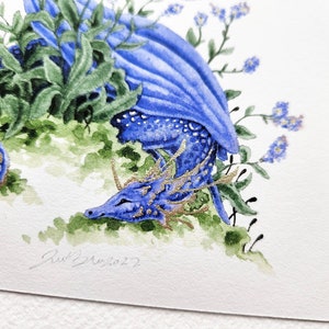 K&ouml;nnte beinhalten: Ein Aquarellbild eines blauen Drachen mit goldenen Akzenten, der sich in einem Bett aus gr&uuml;nen Bl&auml;ttern und blauen Blumen zusammengerollt hat. Die Augen des Drachen sind geschlossen und er scheint zu schlafen. Das Bild ist unten rechts mit "Red 2022" signiert.