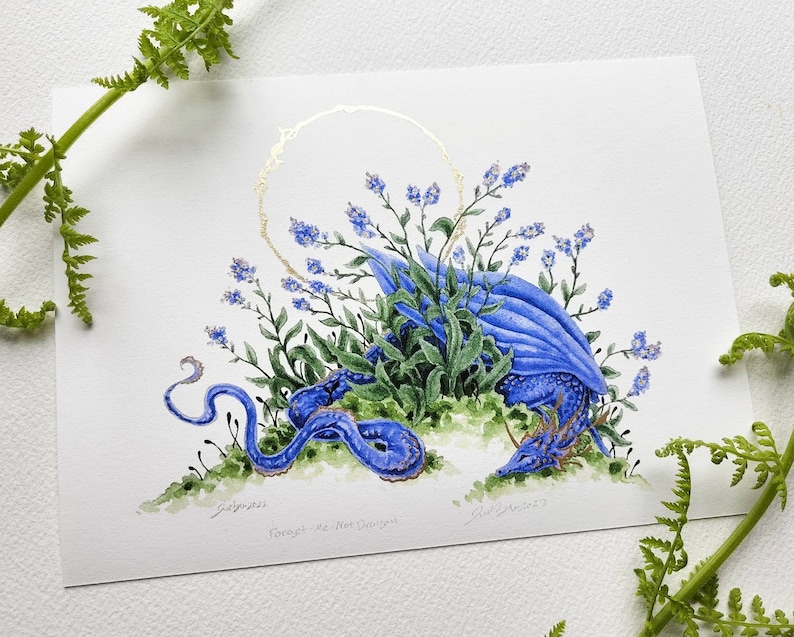 K&ouml;nnte beinhalten: Ein Aquarellbild eines blauen Drachen, der sich in einem Bett aus blauen Vergissmeinnicht-Blumen zusammenrollt. Der Drache hat einen langen, schlanken K&ouml;rper und einen kleinen, zarten Kopf. Die Blumen sind in einem lockeren, flie&szlig;enden Muster um den Drachen herum angeordnet. Das Bild ist vor einem wei&szlig;en Hintergrund mit einem goldenen Kreis im Hintergrund platziert.