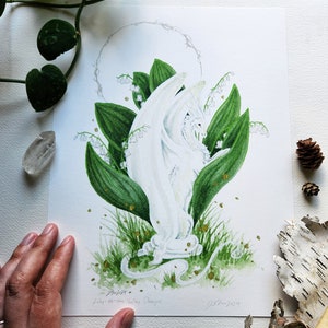 Puede incluir: Ilustraci&oacute;n en acuarela de un drag&oacute;n blanco entre hojas y flores verdes de lirios de los valles. La obra incluye motas doradas y un halo plateado. El texto "Lily-of-the-Valley Dragon" es visible.