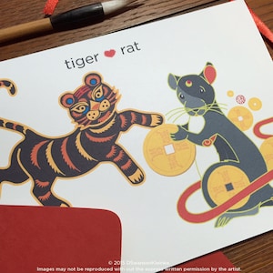 May include: A greeting card with a colorful illustration of a tiger and a rat holding gold coins. The card has the text "tiger ♥ rat" at the top.