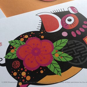 K&ouml;nnte beinhalten: Eine schwarze und rote Illustration eines Schweins mit einer gro&szlig;en roten Blume und gr&uuml;nen Bl&auml;ttern. Das Schwein ist von orangefarbenen und schwarzen Punkten umgeben. Der Text "PIG" und das chinesische Schriftzeichen f&uuml;r "Schwein" befinden sich in der oberen linken Ecke.