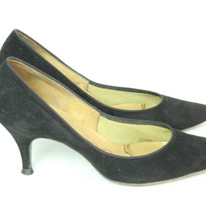 May include: A pair of black suede pumps with stiletto heels. The shoes have a pointed toe and a closed design.
