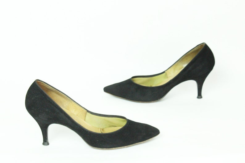 May include: A pair of black suede high-heeled pumps with a pointed toe.