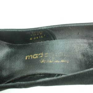 Op de afbeelding: Close-up van de binnenkant van een zwarte su&egrave;de schoen met gouden letters die "made in italy the italian shoe" lezen.