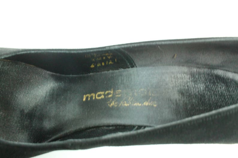 Op de afbeelding: Close-up van de binnenkant van een zwarte su&egrave;de schoen met gouden letters die "made in italy the italian shoe" lezen.