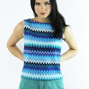May include: A woman wearing a sleeveless blue and white striped top with a turquoise blue denim shorts.