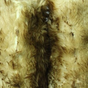 May include: Two pieces of sheepskin with a light brown and white color. The sheepskin has a soft, fluffy texture.