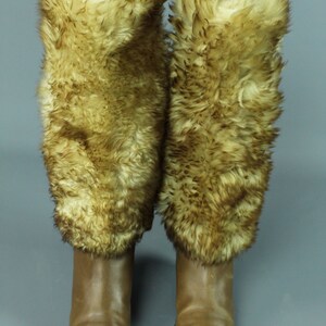 May include: A pair of brown leather boots with faux fur cuffs. The boots have a pointed toe and a low heel.