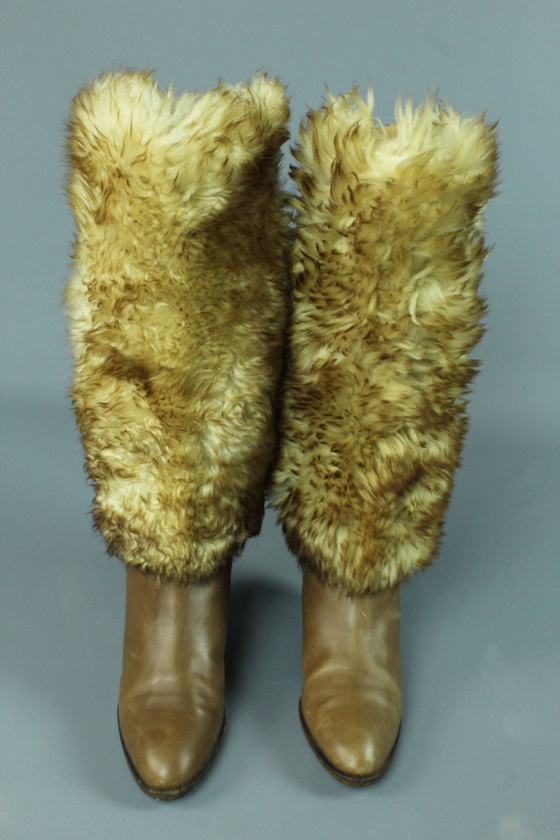 May include: A pair of brown leather boots with faux fur cuffs. The boots have a pointed toe and a low heel.