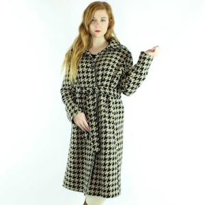 Peut inclure: Un long manteau en tissu à motif pied-de-poule noir et beige avec une fermeture éclair et une ceinture. Le manteau a un col et des manches longues.