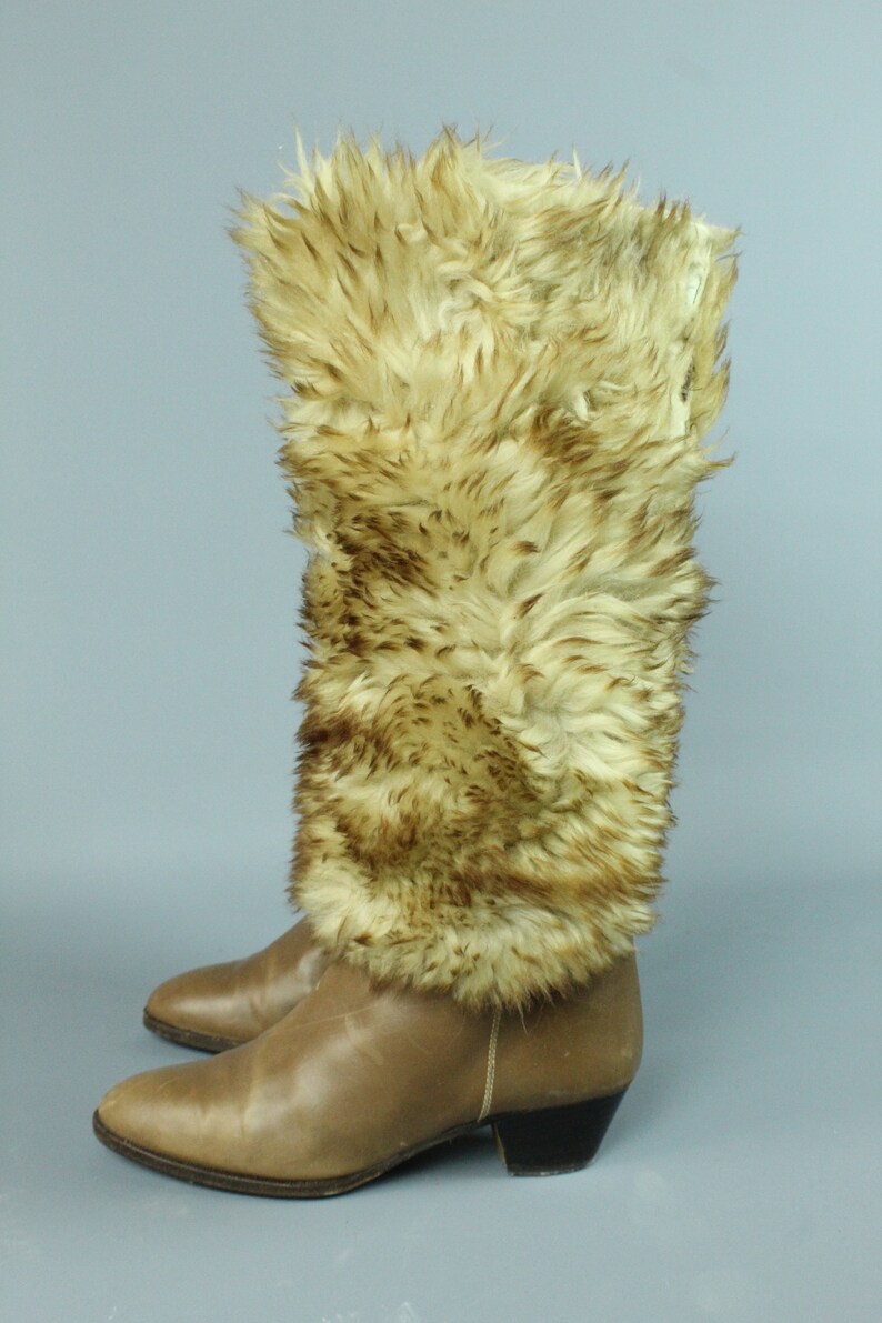 May include: Brown leather boots with a faux fur cuff. The fur is a light brown color with darker brown streaks.