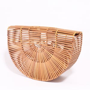 May include: A half-circle shaped woven bamboo handbag with a natural brown color.