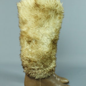 May include: A pair of brown leather knee-high boots with a faux fur cuff. The boots have a pointed toe and a low block heel.