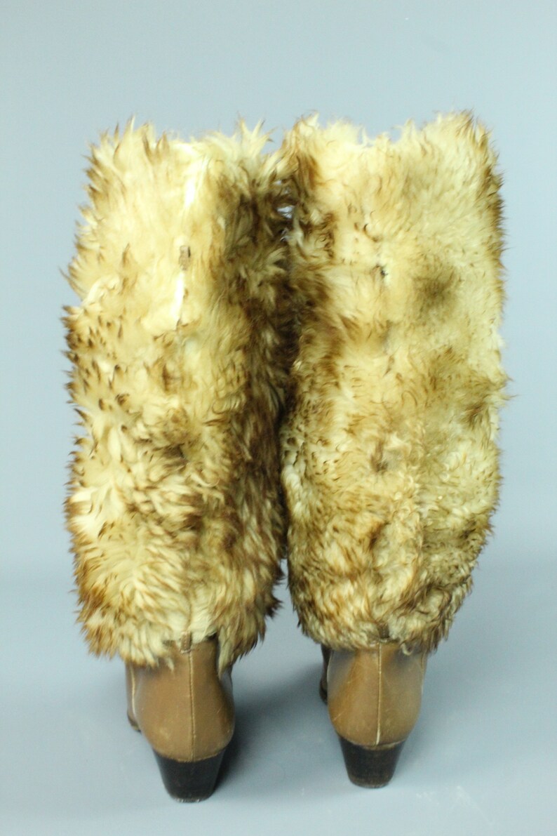 May include: A pair of brown leather boots with faux fur trim. The boots have a high heel and a pointed toe.