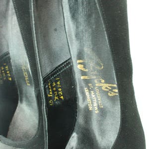 Op de afbeelding: Zwarte su&egrave;de schoenen met een gouden inscriptie die "Prick's Louisville, St. Matthews, Lexington 620121 13 8000 7120 &euro;20/21" luidt.