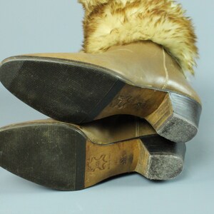 May include: Brown leather boots with a fur cuff. The boots have a wooden heel and a rubber sole.