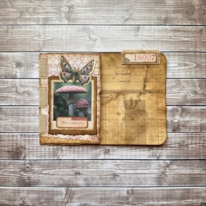 May include: A vintage-style journal with a brown leather cover and a decorative butterfly and mushroom illustration. The journal is labeled "No. 18007 Accounts Receivable Ledger".