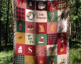 Könnte beinhalten: Eine Weihnachtsdecke mit Patchwork-Design. Die Decke zeigt Quadrate mit festlichen Bildern wie einem Weihnachtsbaum, einem Schneeflocke und einem Strumpf. Die Decke hat ein rot-, grün- und goldfarbenes Farbschema und enthält den Text "The Smiths" und "Joy".