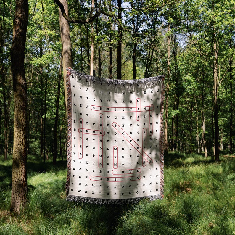 May include: A white woven blanket with a red and black word search pattern. The pattern includes the words "LOVE", "MOM", "JESSICA", and "CHRISTMAS".