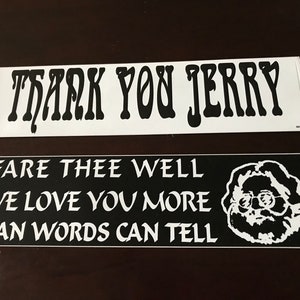 May include: Two black and white bumper stickers with a Grateful Dead theme. The top sticker says "Thank You Jerry" in a stylized font. The bottom sticker says "Fare Thee Well We Love You More Than Words Can Tell" and features a black and white illustration of Jerry Garcia.