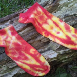 May include: A pair of red and yellow tie-dye socks. The socks are made of a soft, comfortable material and have a unique, colorful design.