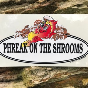 May include: A white sticker with a red and yellow cartoon fish surrounded by brown mushrooms. The fish has a chef's hat and is laying on its side. The text "PHREAK ON THE SHROOMS" is in a black oval on the sticker. The copyright text "© 1997 RJD This is a Parody" is at the bottom of the sticker.