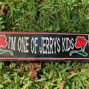 May include: Black and red sticker with white text that reads "I'm one of Jerry's Kids". The sticker has two red roses on either side of the text.