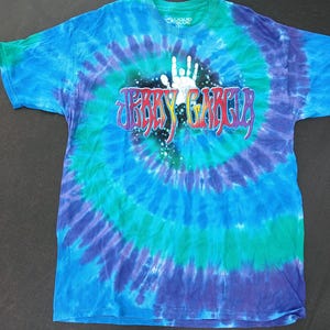 May include: A tie-dye t-shirt with a spiral pattern in shades of blue, green, and purple. The shirt features the text "Jerry Garcia" in a colorful, stylized font, along with a white handprint graphic. The shirt is made of a soft material.