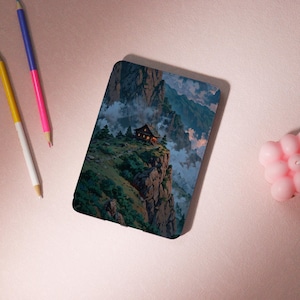 May include: A rectangular phone case featuring a scenic landscape of a mountain range with a small cabin on a cliff. The artwork depicts a cabin with lights on, surrounded by green trees, clouds, and mountains. The case has a glossy finish.