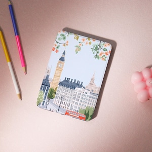 May include: A white and blue illustrated case for an e-reader with a depiction of Big Ben and other London landmarks. The case has a floral design with pink and orange flowers.