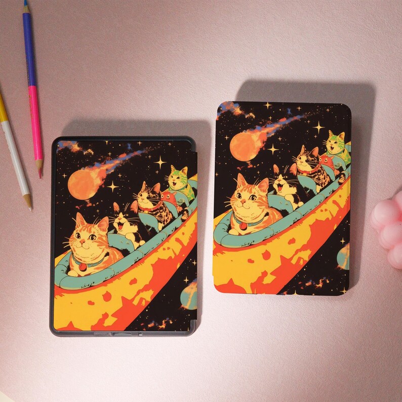 Peut inclure: Deux &eacute;tuis rectangulaires noirs avec une illustration color&eacute;e de chats dans un vaisseau spatial. Les chats sont dans un vaisseau spatial bleu et jaune avec une com&egrave;te rouge et orange en arri&egrave;re-plan. Le fond est noir avec des &eacute;toiles.