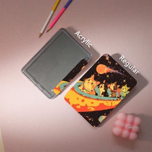 Peut inclure: Un &eacute;tui en acrylique transparent et une carte r&eacute;guli&egrave;re avec une illustration sur le th&egrave;me de l'espace de chats dans un vaisseau spatial. La carte a un fond noir avec des plan&egrave;tes et des &eacute;toiles. Le texte "Acrylic" et "Regular" est visible.