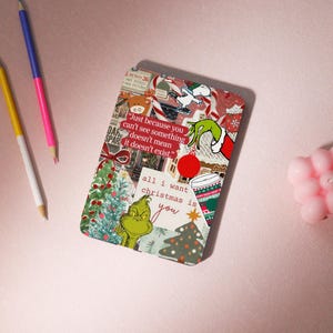 May include: A rectangular Christmas-themed phone case with a collage design. The case features images of the Grinch, Snoopy, Christmas trees, and text that reads "all I want christmas is you". The case also has the quote "Just because you can't see something doesn't mean it doesn't exist."