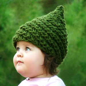 May include: A baby wearing a green knitted hat with a pointed top. The hat is made with a simple stitch pattern and has a soft, cosy look.