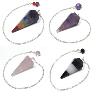 May include: Four crystal pendulums with silver chains and decorative beads. The pendulums are in various colors: a rainbow-colored one, a purple one, a pink one, and a black and white one. Each pendulum is a different type of crystal.