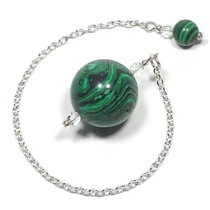 May include: A green malachite pendulum with a silver chain. The pendulum has a round, swirling pattern.