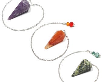 May include: Three crystal pendulums with silver chains and decorative beads. The crystals are purple, orange, and green with various patterns. The pendulums are used for divination and spiritual practices.