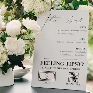 May include: A white sign with black text that reads "the bar" and lists wine, beer, and spirits. The sign also includes a cash tip option and a QR code for scanning.