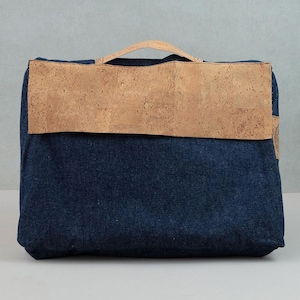 May include: A blue denim and cork laptop bag with a brown leather handle.