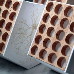 May include: Three white and brown wooden boxes with cork inserts. The boxes are stacked on top of each other and have a white background.