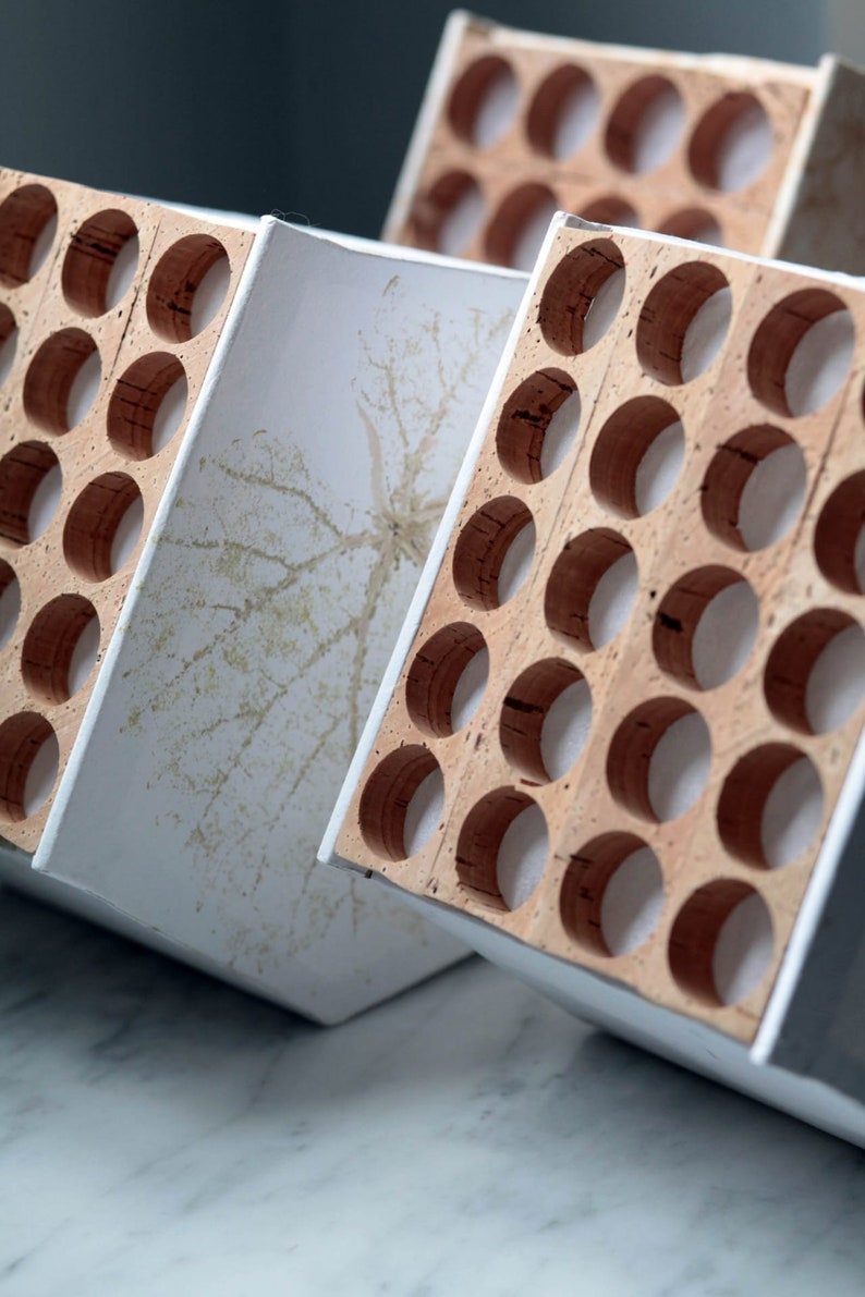 May include: Three white and brown wooden boxes with cork inserts. The boxes are stacked on top of each other and have a white background.