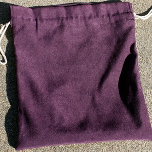 May include: A dark purple drawstring bag made of fabric. The bag is empty and has a white drawstring.