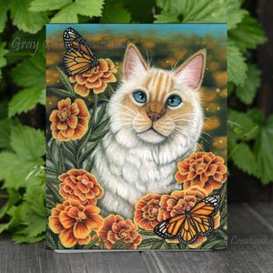 May include: A white cat with orange tabby markings sits in a field of orange marigolds.  Two butterflies are perched on the flowers.  The cat has blue eyes and a sweet expression.